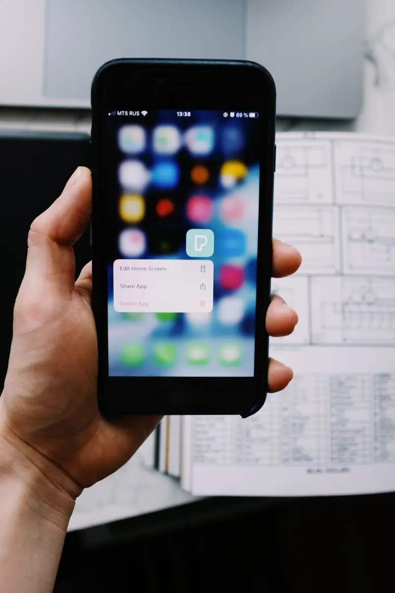 Phone next to paper wireframes of an app