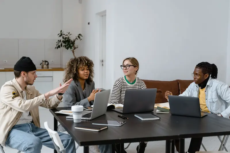 Small team discussing a project around a table with laptops